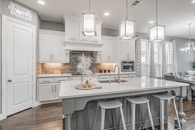 kitchen featuring stainless steel oven, hanging light fixtures, and white cabinetry