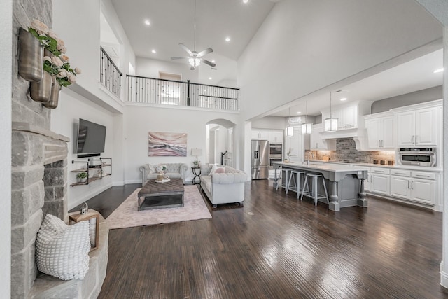 living room featuring a high ceiling, ceiling fan, and dark hardwood / wood-style flooring