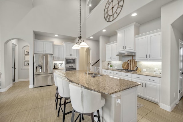 kitchen featuring white cabinets, appliances with stainless steel finishes, a center island with sink, and sink