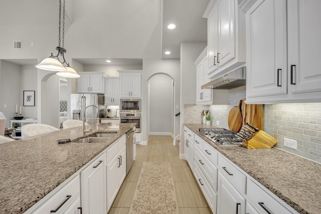 kitchen featuring decorative light fixtures, sink, white cabinets, light stone counters, and stainless steel appliances