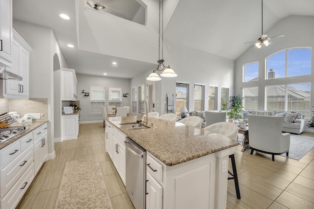 kitchen with sink, an island with sink, a kitchen bar, white cabinetry, and stainless steel appliances