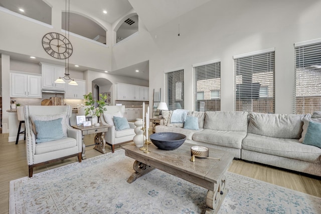 living room featuring a towering ceiling and light hardwood / wood-style flooring