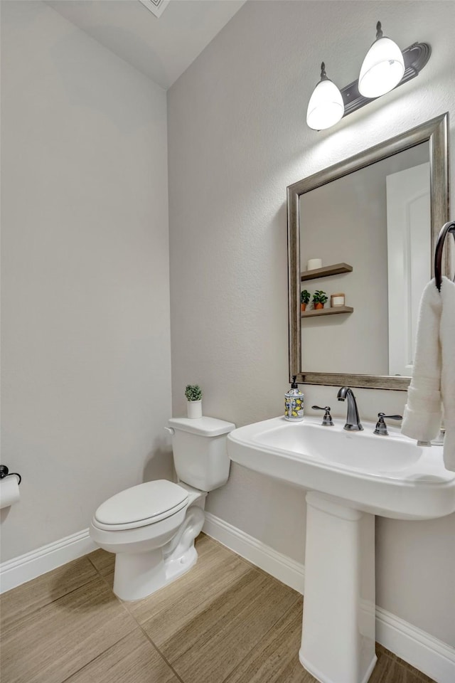 bathroom with wood-type flooring, toilet, and sink