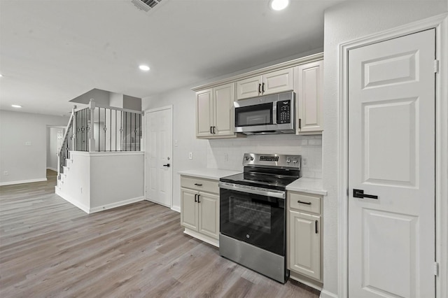 kitchen with backsplash, stainless steel appliances, and light wood-type flooring