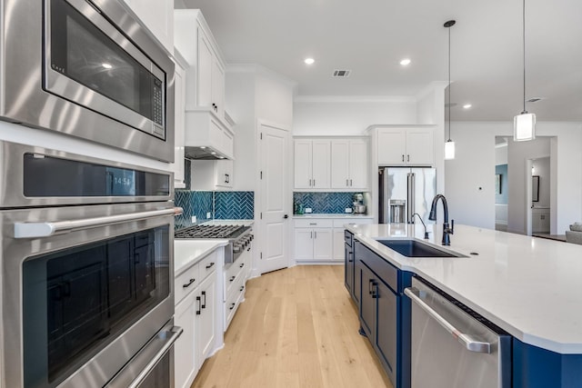 kitchen with appliances with stainless steel finishes, tasteful backsplash, sink, decorative light fixtures, and white cabinetry