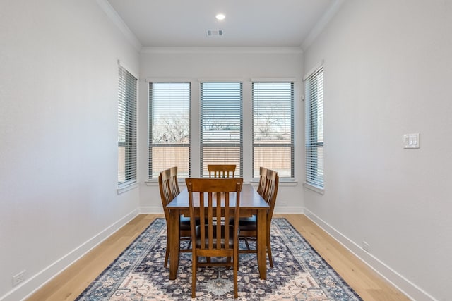 dining area with hardwood / wood-style floors, a healthy amount of sunlight, and ornamental molding