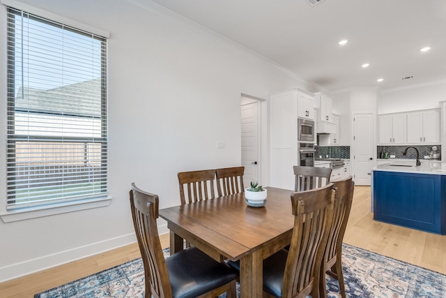 dining space featuring a healthy amount of sunlight, crown molding, sink, and light hardwood / wood-style floors