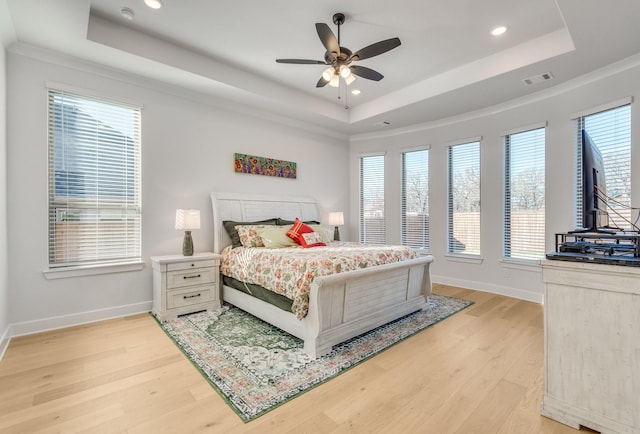 bedroom with light hardwood / wood-style flooring, a raised ceiling, ceiling fan, and crown molding