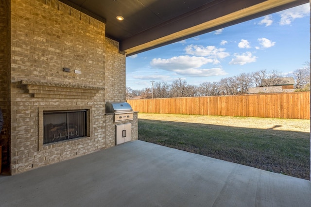 view of patio / terrace with grilling area and an outdoor brick fireplace