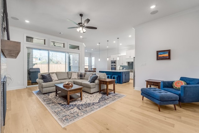 living room with ceiling fan, plenty of natural light, and light wood-type flooring