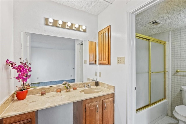 full bathroom with vanity, bath / shower combo with glass door, and toilet