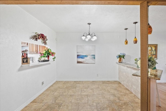 unfurnished dining area with a chandelier and a textured ceiling