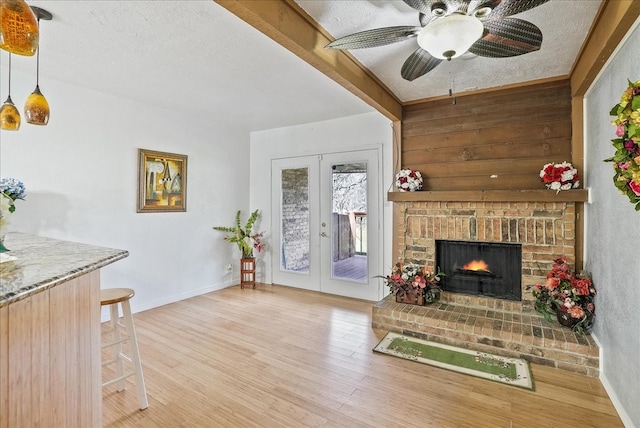 living room with french doors, beamed ceiling, a textured ceiling, and light hardwood / wood-style flooring