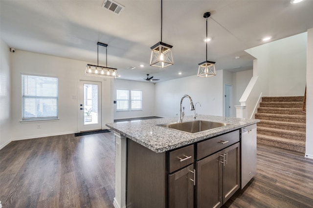 kitchen featuring dishwasher, sink, hanging light fixtures, dark brown cabinetry, and light stone countertops