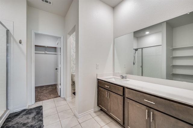 bathroom with tile patterned floors, toilet, a shower with shower door, and vanity