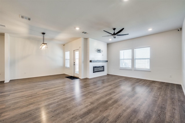 unfurnished living room with a large fireplace, ceiling fan, and dark hardwood / wood-style flooring