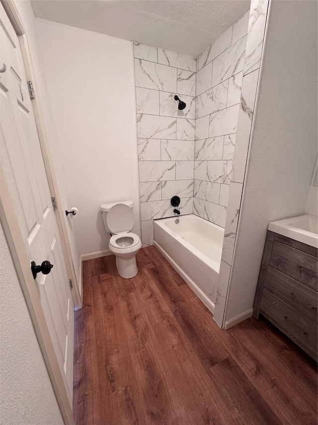 bathroom with a textured ceiling, toilet, tiled shower / bath combo, and hardwood / wood-style flooring