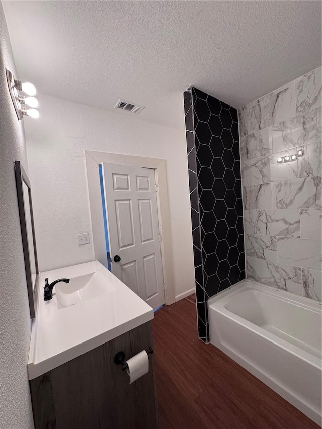 bathroom with hardwood / wood-style flooring, vanity, a textured ceiling, and tiled shower / bath combo