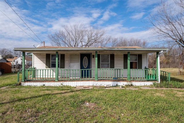 ranch-style house featuring covered porch and a front yard