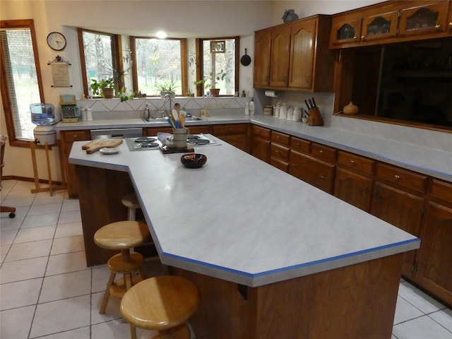 kitchen with a breakfast bar, light tile patterned floors, tasteful backsplash, light countertops, and a sink