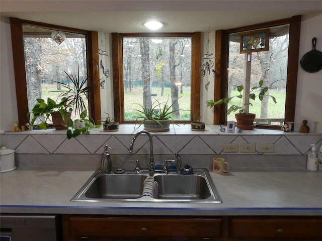 kitchen featuring stainless steel dishwasher, light countertops, and a sink