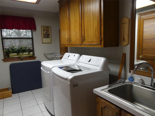 washroom featuring light tile patterned floors, washer and clothes dryer, a sink, and cabinet space