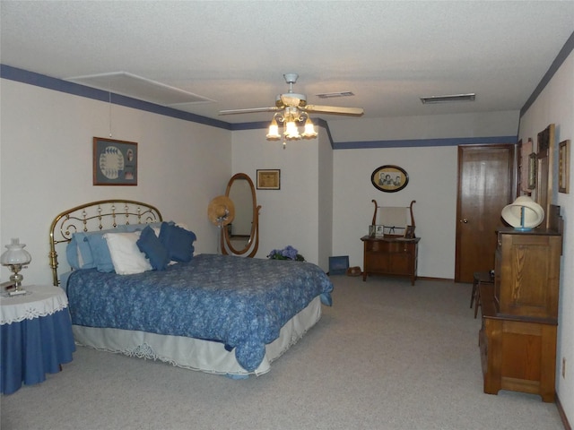 carpeted bedroom featuring attic access, a textured ceiling, visible vents, and a ceiling fan