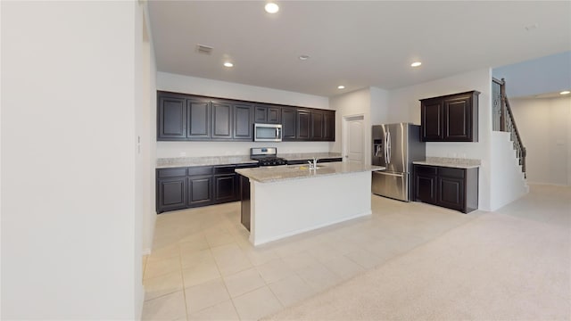 kitchen featuring dark brown cabinetry, sink, stainless steel appliances, an island with sink, and light tile patterned floors