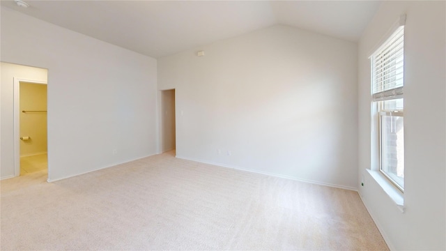 carpeted spare room with vaulted ceiling and a healthy amount of sunlight