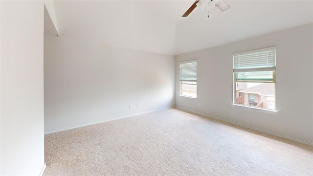 unfurnished room with light colored carpet, vaulted ceiling, and ceiling fan