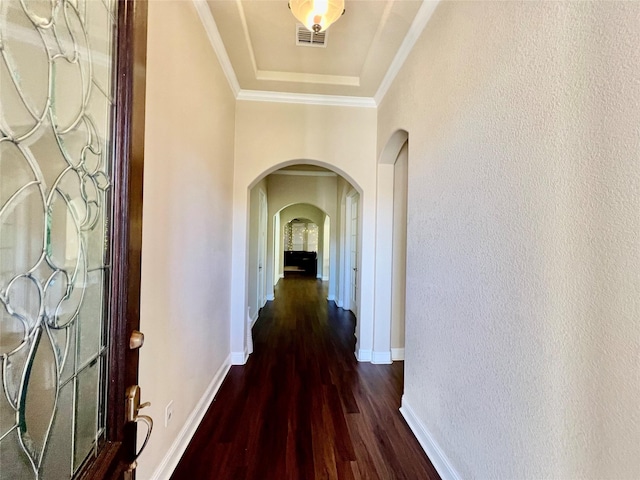 corridor featuring a raised ceiling, crown molding, and dark hardwood / wood-style flooring