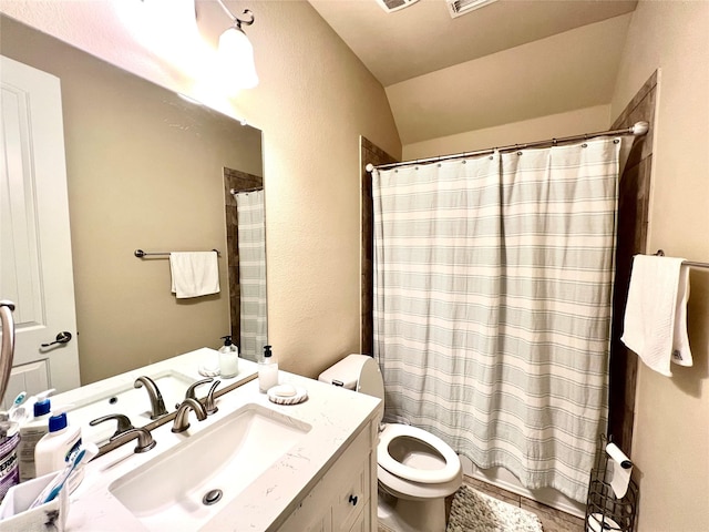 bathroom featuring vanity, lofted ceiling, tile patterned floors, toilet, and walk in shower