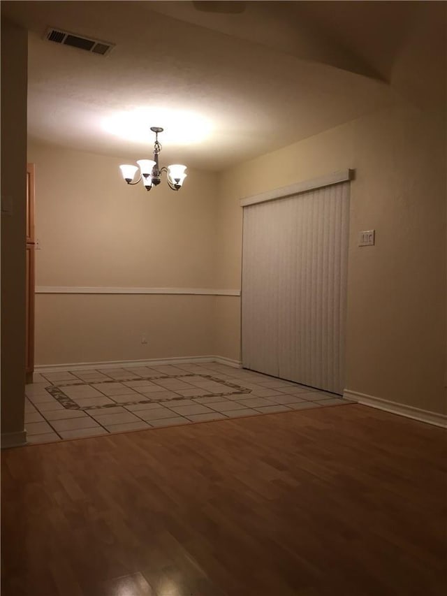 unfurnished room featuring a notable chandelier and wood-type flooring