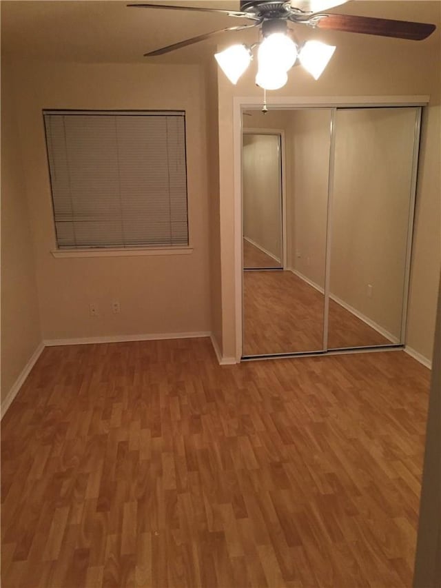 unfurnished bedroom featuring hardwood / wood-style floors, ceiling fan, and a closet