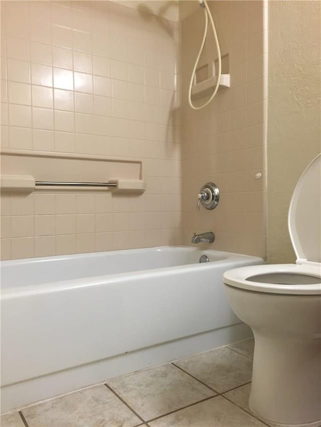 bathroom featuring tile patterned floors, tiled shower / bath combo, and toilet