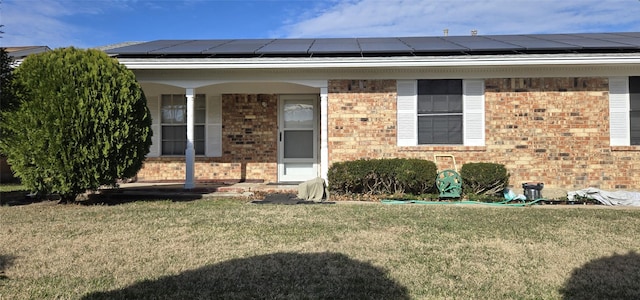 doorway to property featuring solar panels and a yard