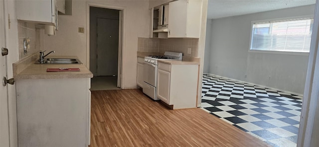 kitchen with decorative backsplash, light wood-type flooring, range with gas cooktop, sink, and white cabinetry