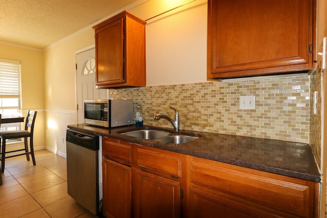 kitchen featuring sink, stainless steel appliances, tasteful backsplash, dark stone counters, and light tile patterned floors