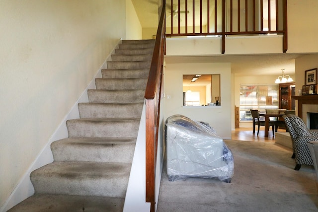 stairs featuring carpet floors, a high ceiling, and a notable chandelier