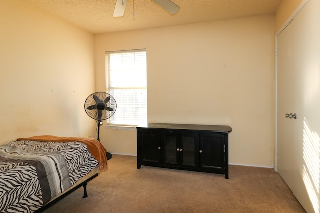 carpeted bedroom with ceiling fan and a textured ceiling