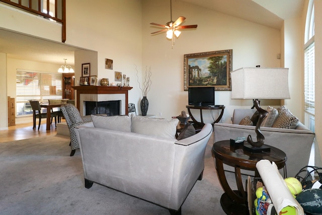 living room with ceiling fan with notable chandelier, light colored carpet, and high vaulted ceiling