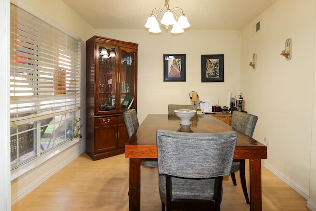 dining space with light wood-type flooring and an inviting chandelier