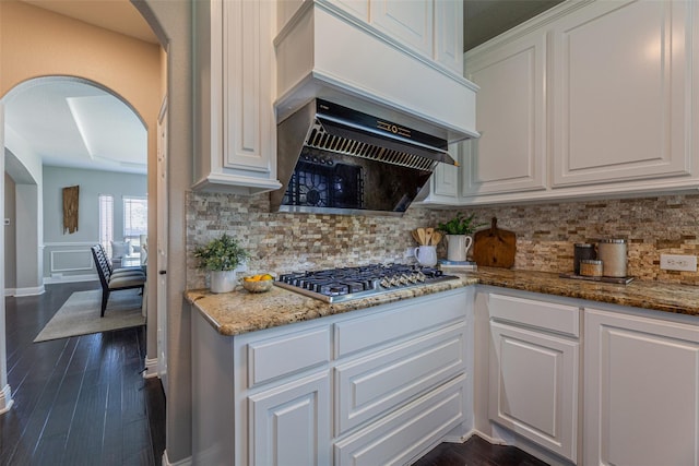 kitchen featuring stone counters, premium range hood, stainless steel gas stovetop, tasteful backsplash, and white cabinets