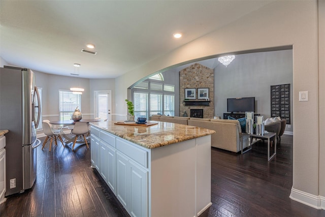 kitchen featuring a kitchen island, pendant lighting, stainless steel refrigerator, white cabinetry, and dark hardwood / wood-style flooring