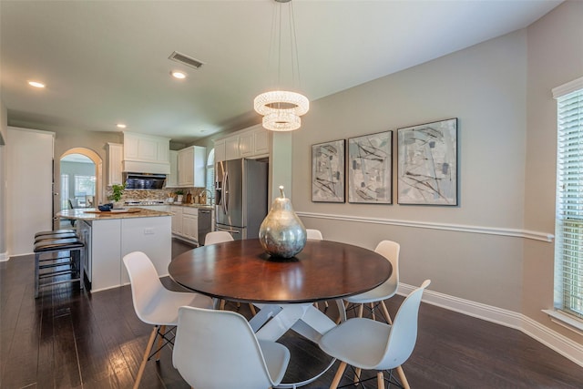 dining area featuring dark wood-type flooring, a notable chandelier, and a wealth of natural light