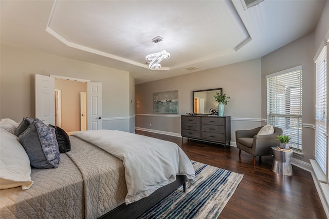 bedroom with dark hardwood / wood-style flooring and a raised ceiling