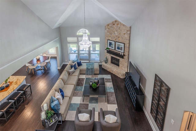 living room with high vaulted ceiling, a stone fireplace, a chandelier, and dark hardwood / wood-style flooring