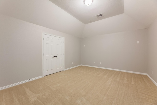 carpeted empty room featuring lofted ceiling