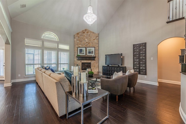 living room featuring dark wood-type flooring, a fireplace, high vaulted ceiling, and a chandelier