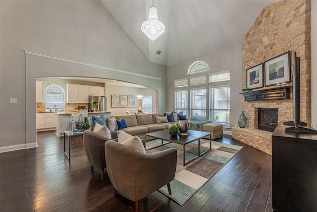 living room featuring a stone fireplace, sink, high vaulted ceiling, and dark hardwood / wood-style flooring